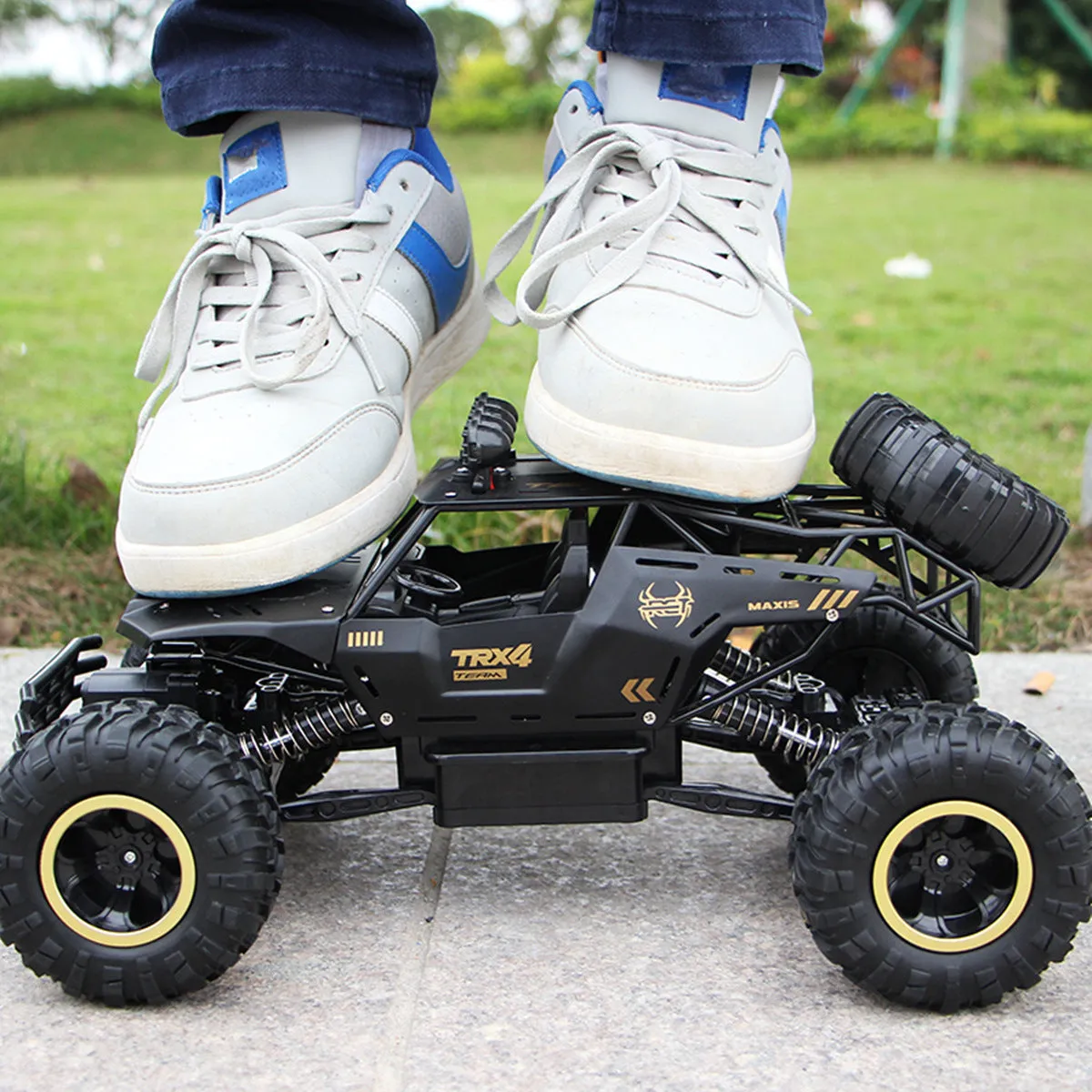 Black and silver remote control off-road car on rough terrain showing four-wheel drive and climbing capability.