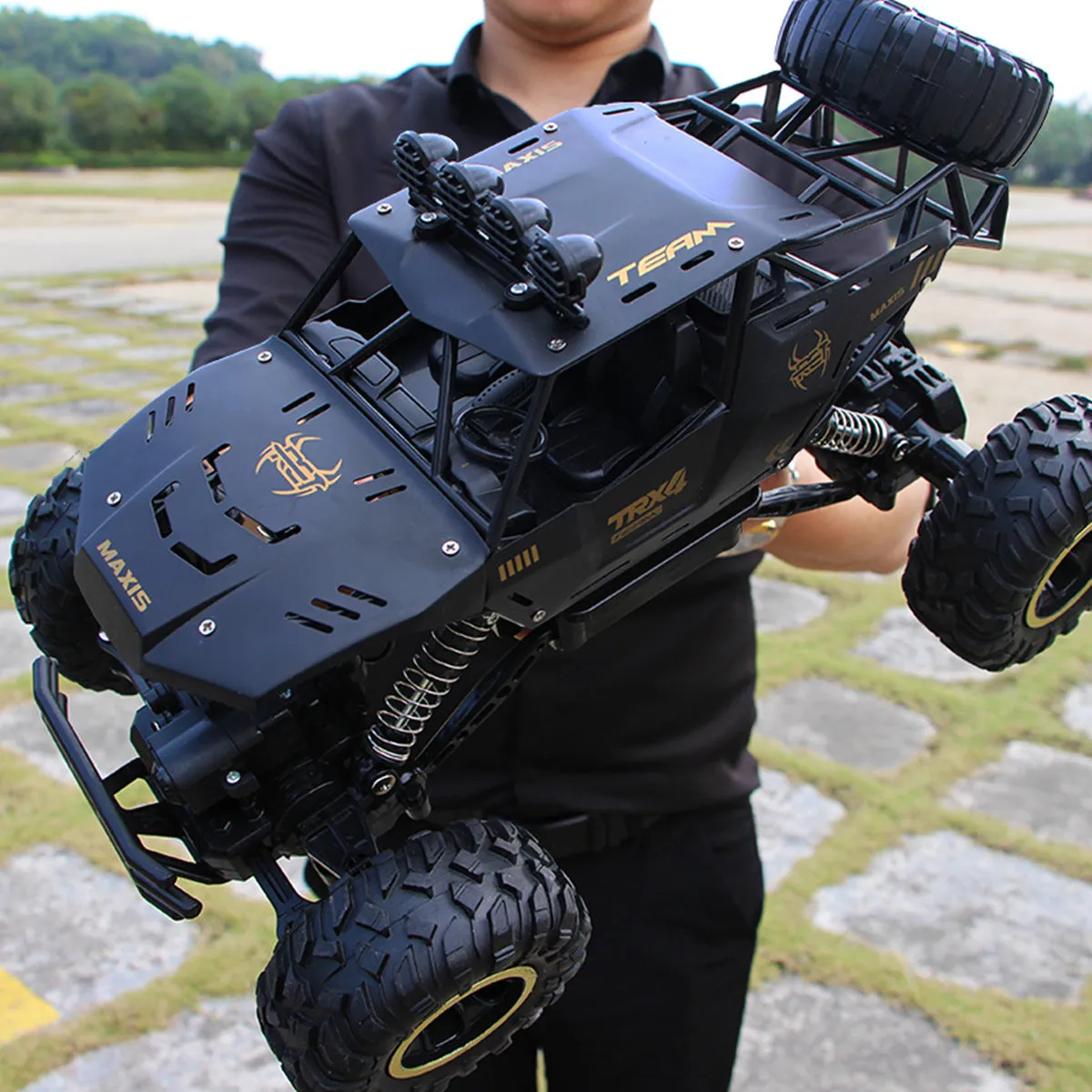 Black and silver remote control off-road car on rough terrain showing four-wheel drive and climbing capability.