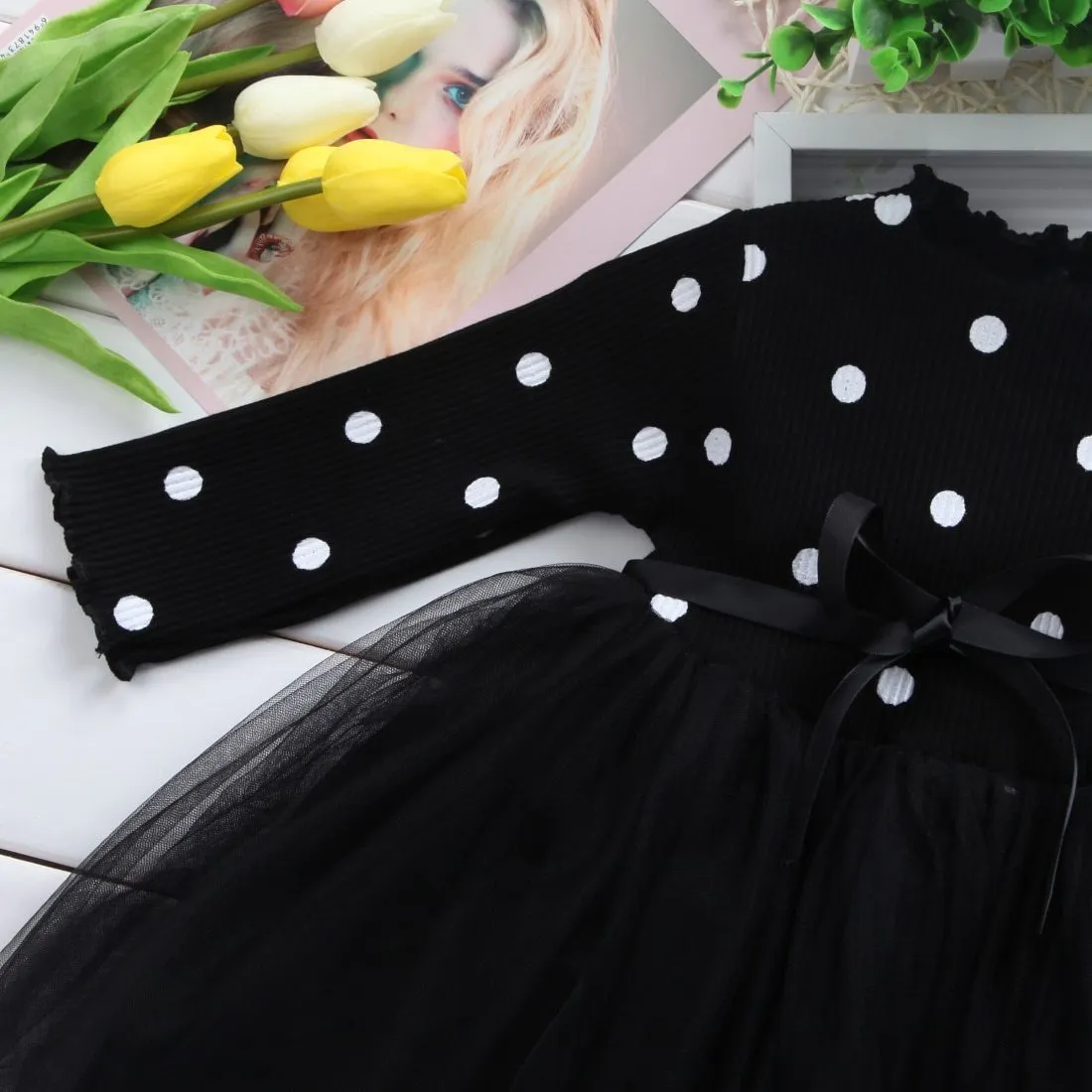 Baby girl wearing a long sleeve black tutu lace dress for a first birthday party.