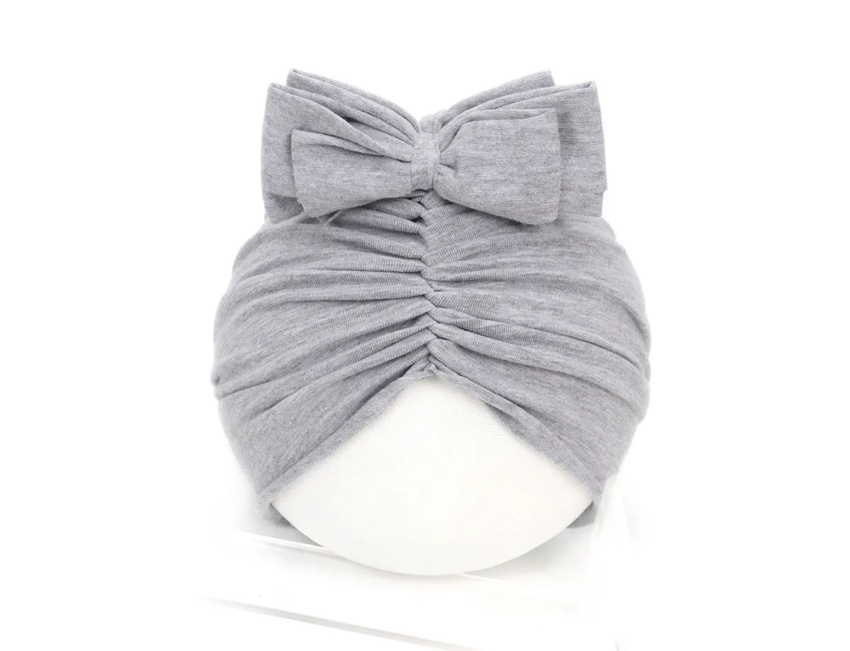 Baby girl wearing a soft, knitted purple turban-style hat on a white background.