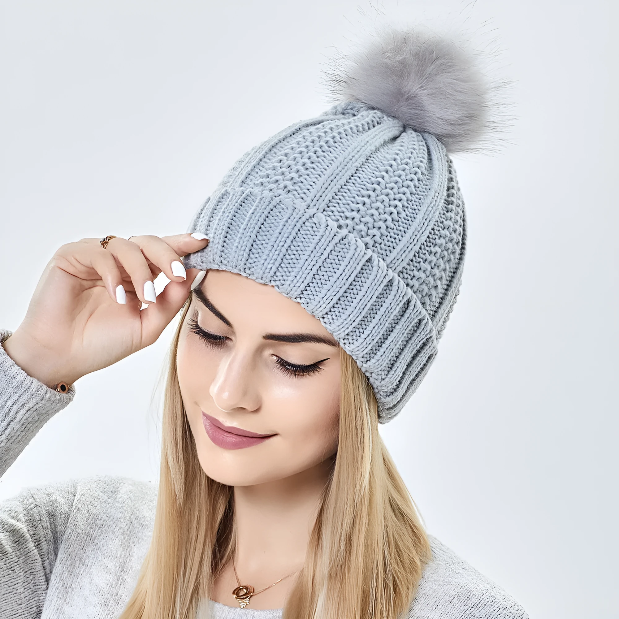 Women's knitted beanie hat with faux fur pom pom and satin lining in multiple colour options.