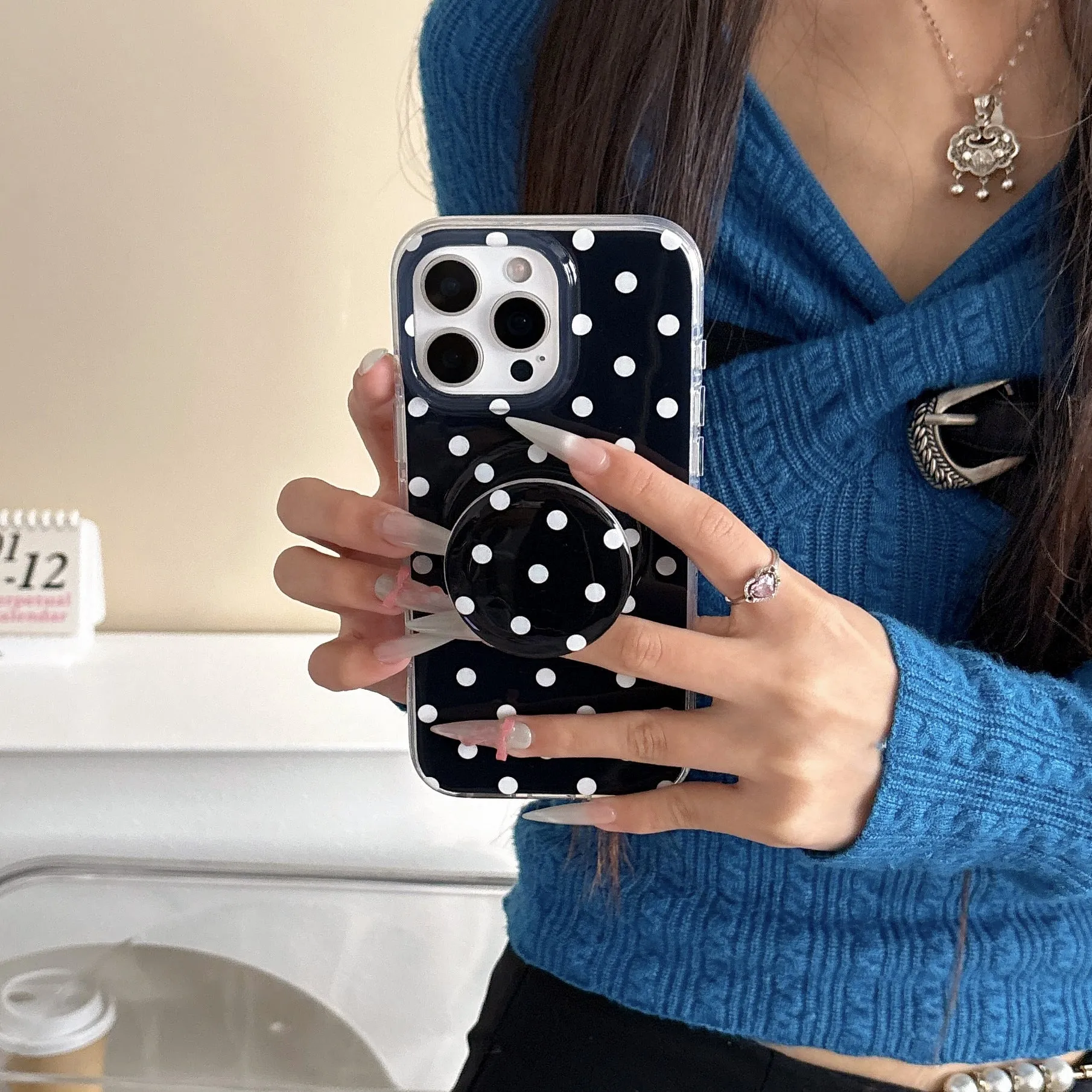 Polka dot phone case with magnetic bracket for iPhone in black showing kickstand