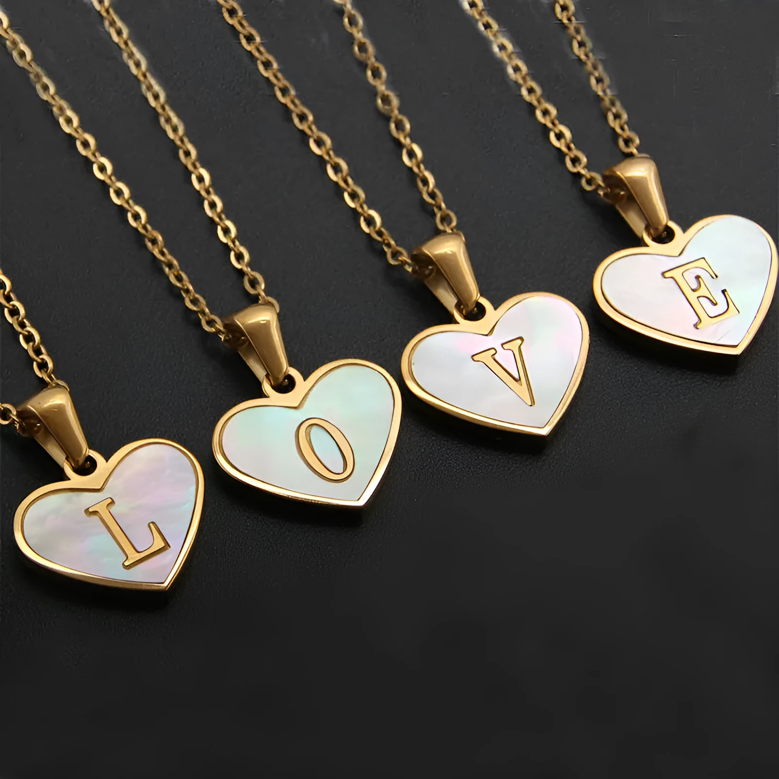 Gold-plated heart-shaped white shell initial necklace on a model, showing the adjustable clavicle chain.