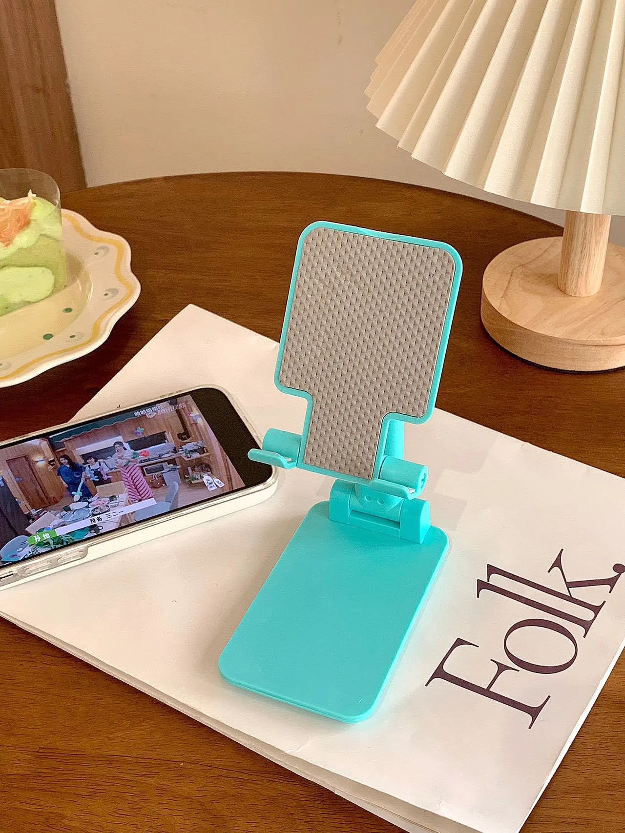 Folding plastic mobile phone stand in pearl white on a flat surface