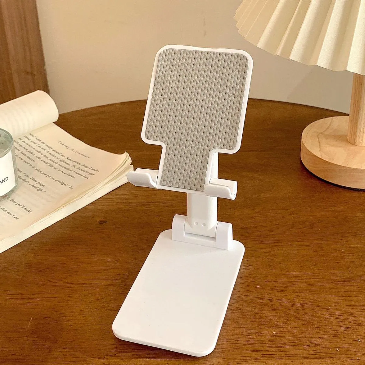 Folding plastic mobile phone stand in pearl white on a flat surface