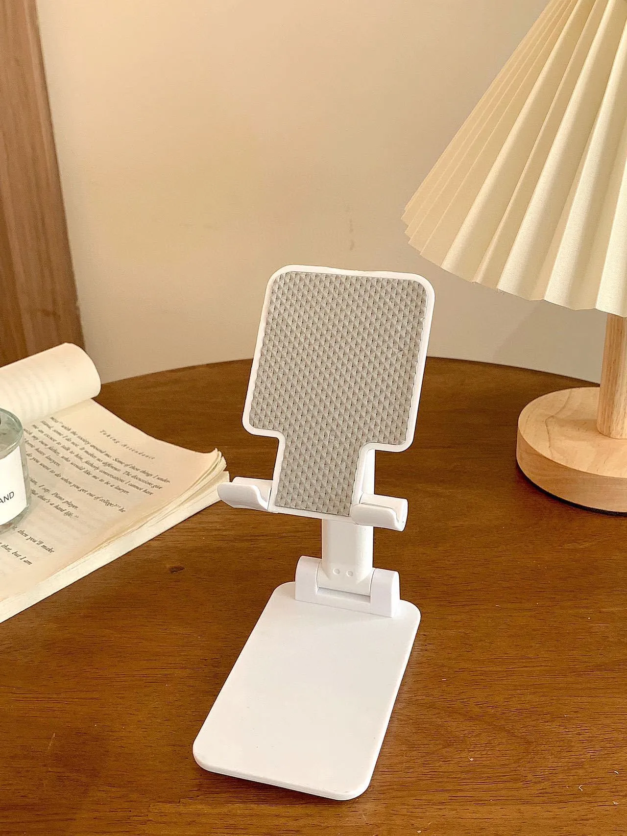 Folding plastic mobile phone stand in pearl white on a flat surface