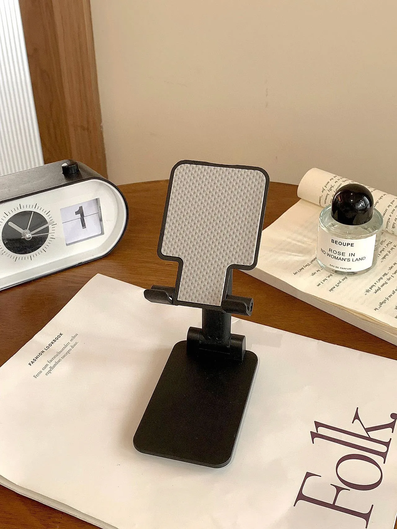 Folding plastic mobile phone stand in pearl white on a flat surface