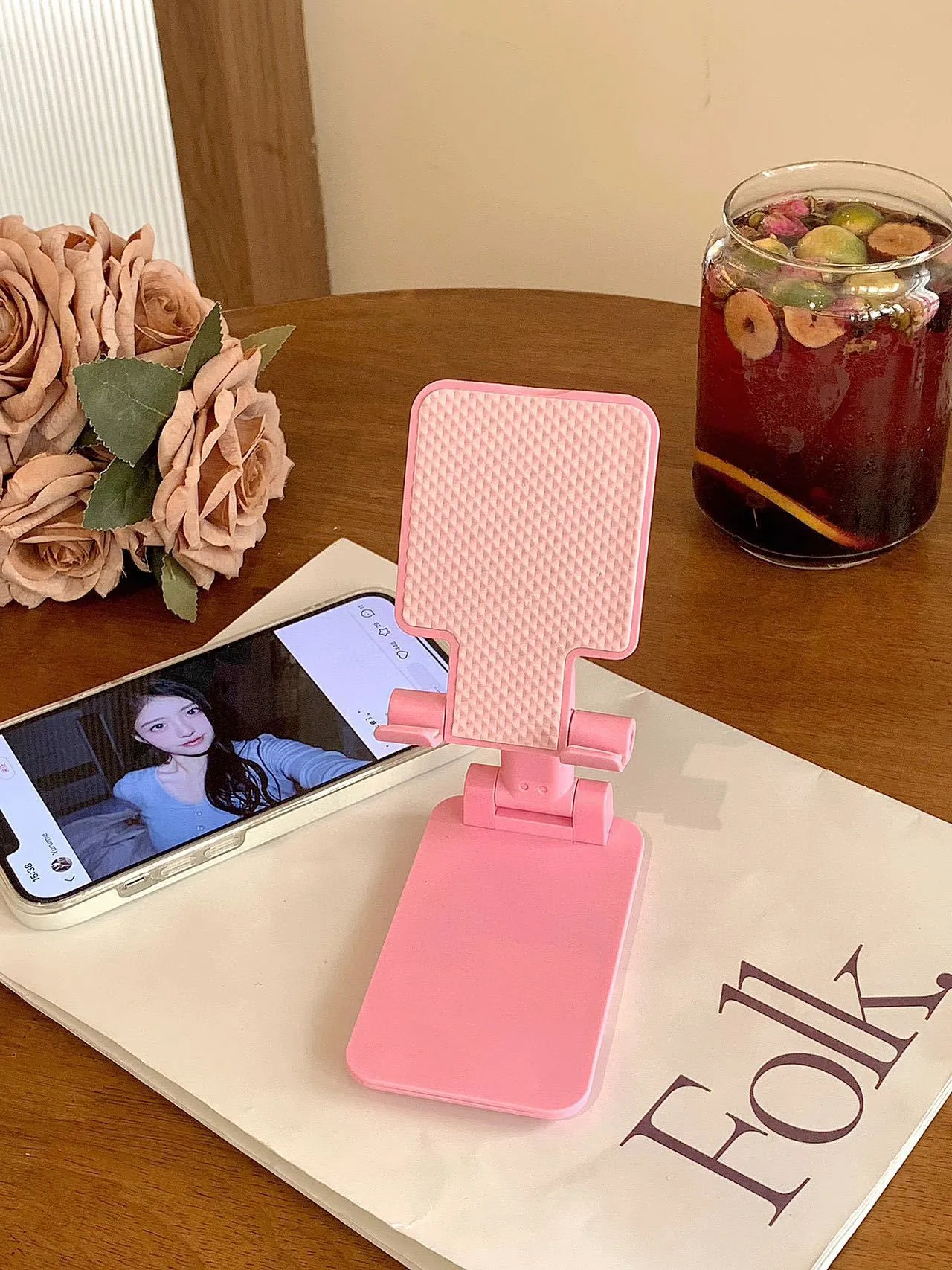 Folding plastic mobile phone stand in pearl white on a flat surface