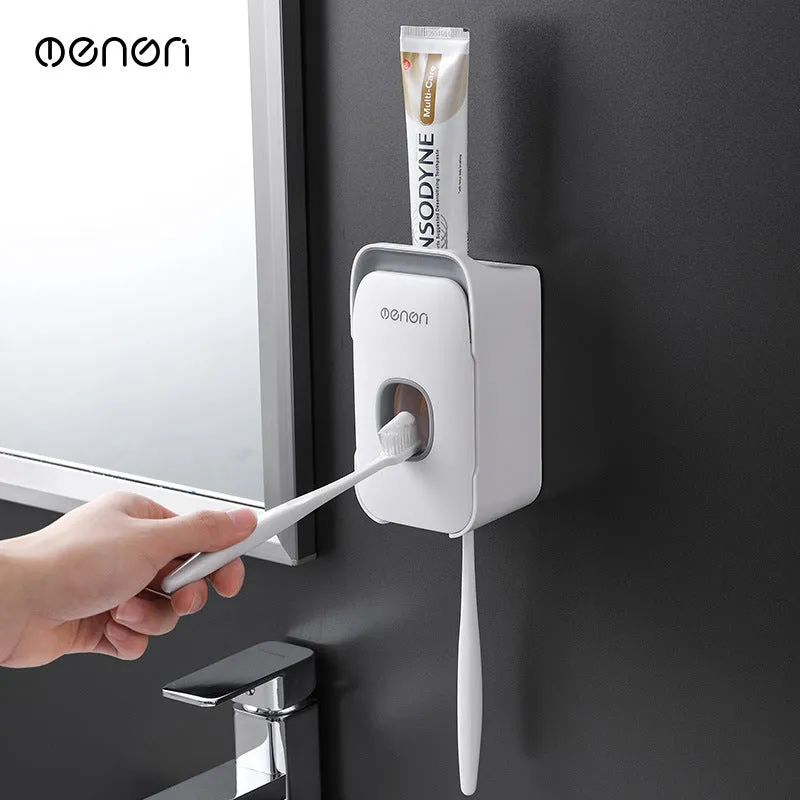 Automatic toothpaste dispenser in grey, blue, and pink colours on a bathroom countertop.