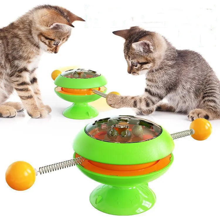 Rotating turntable cat toy with transparent compartment containing catnip balls and suction cup base