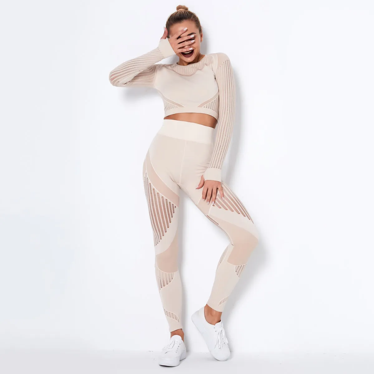 Woman wearing a seamless long-sleeved yoga suit in a neutral colour, demonstrating a stretch pose.