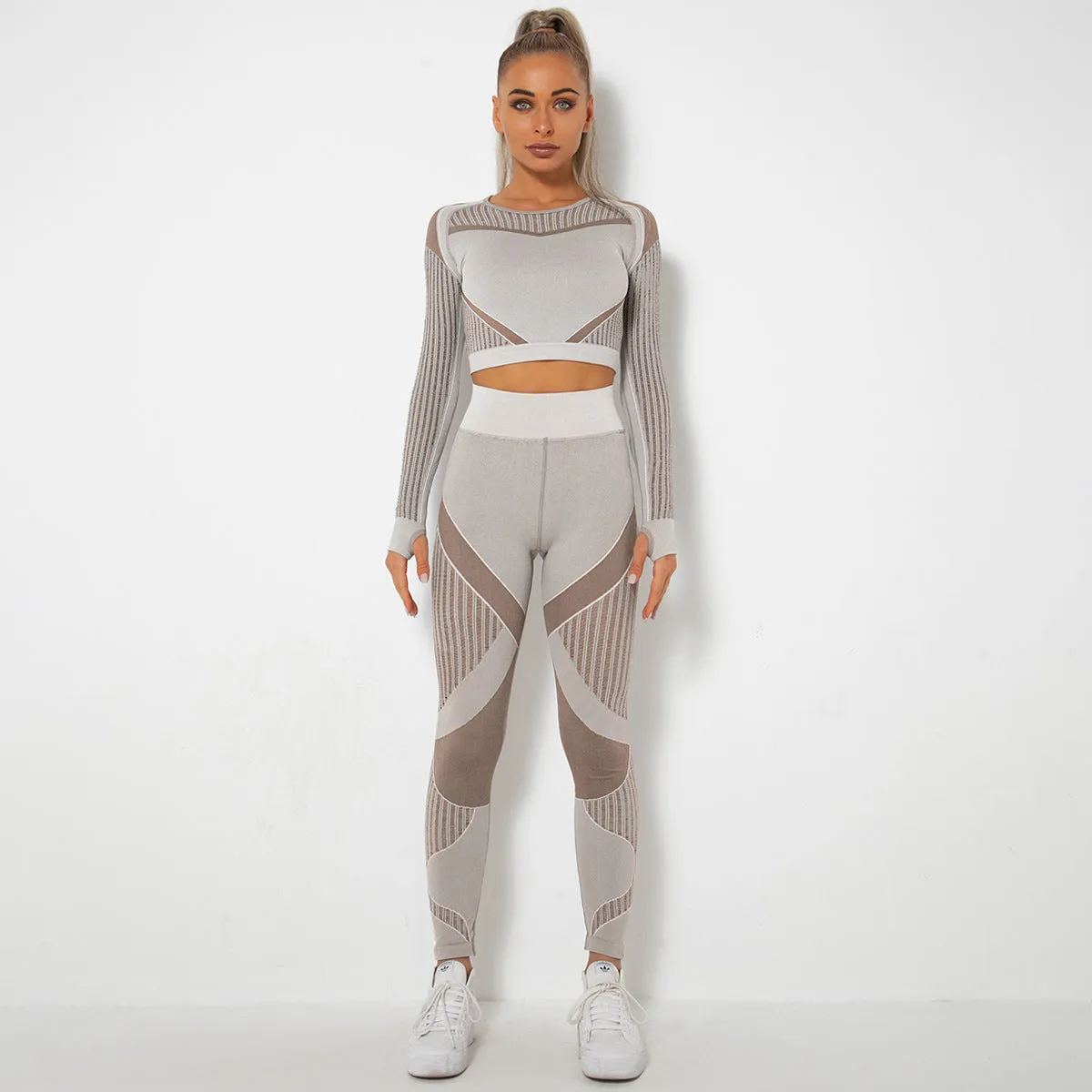 Woman wearing a seamless long-sleeved yoga suit in a neutral colour, demonstrating a stretch pose.