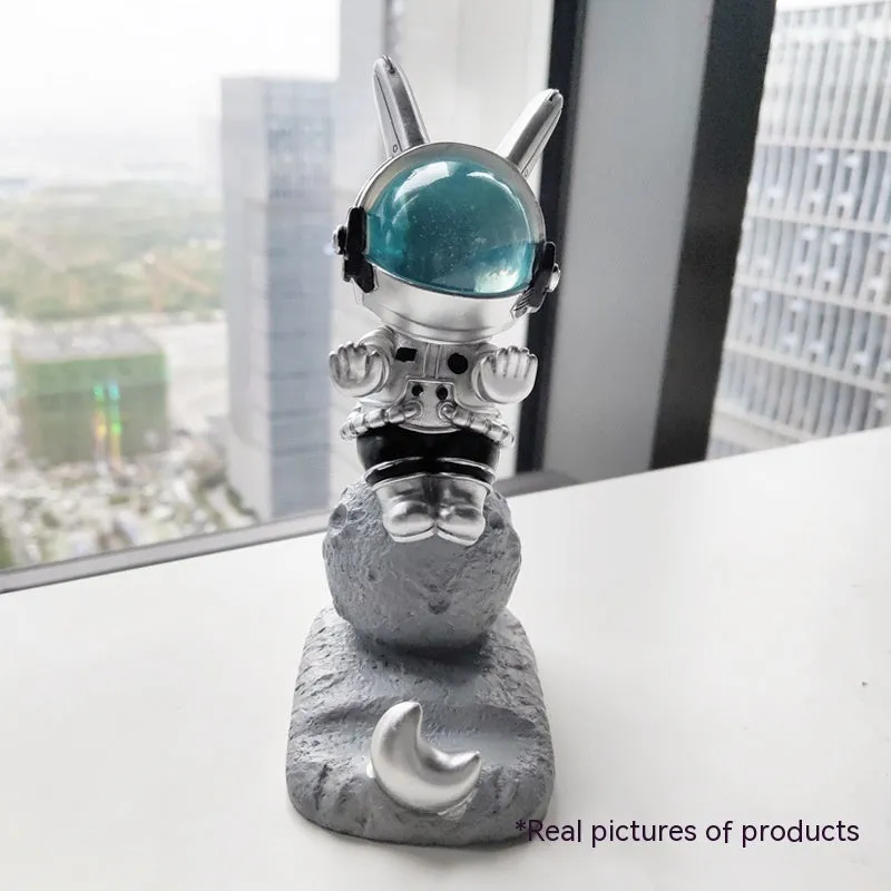 Space Rabbit resin phone stand in pink holding a smartphone on a desktop