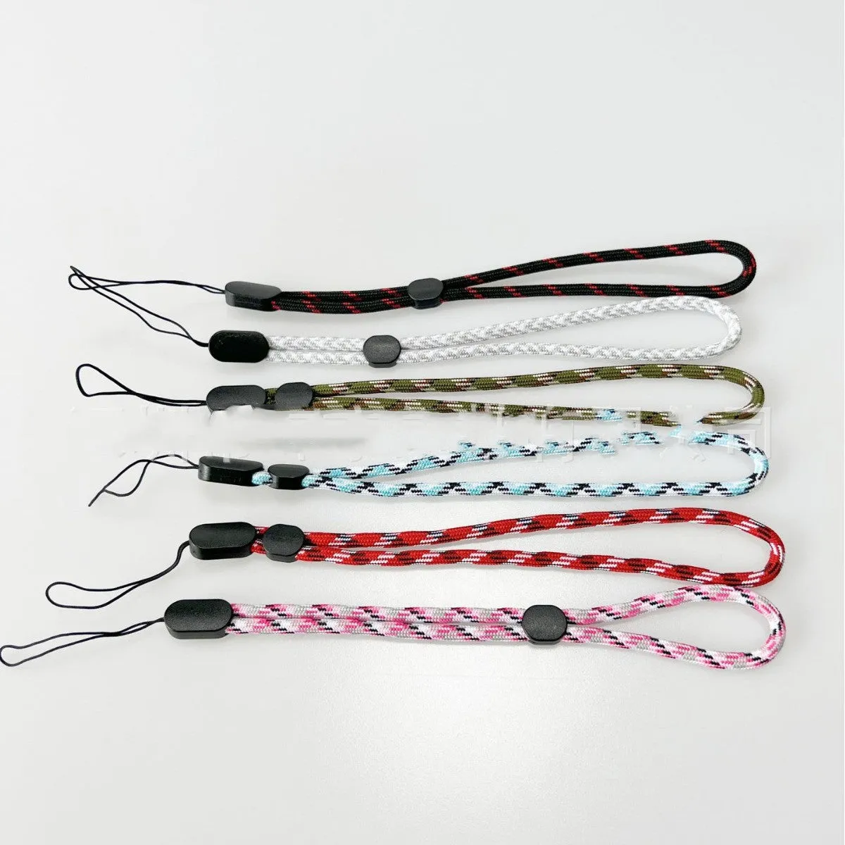 Adjustable round woven mobile phone lanyard in pink, white, and blue colours on a white background
