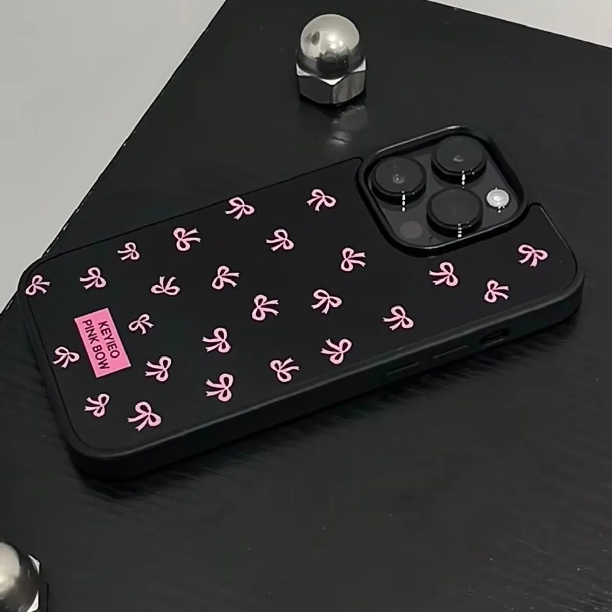 Black silicone iPhone case with sweet bow design placed on a white surface, all-inclusive back and side coverage