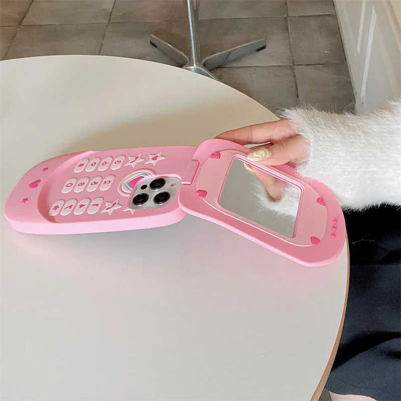 A light pink silicone iPhone case shaped like a flip phone with a built-in mirror on the front.