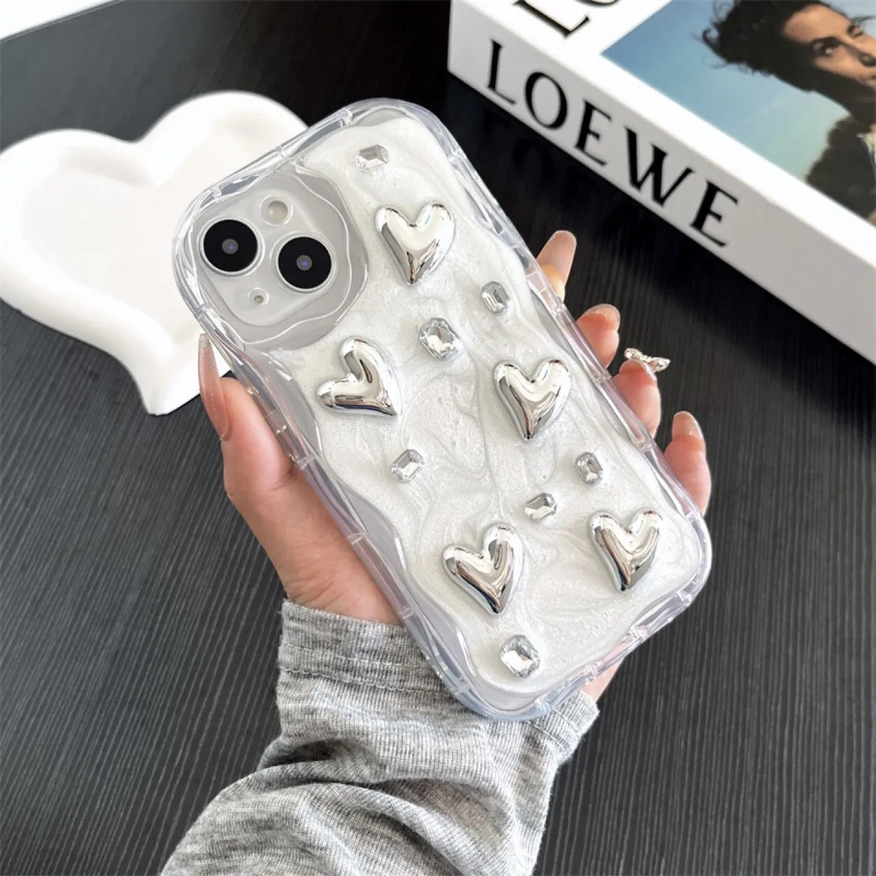 Transparent TPU phone case with three-dimensional silver love gem rhinestone heart design on white background