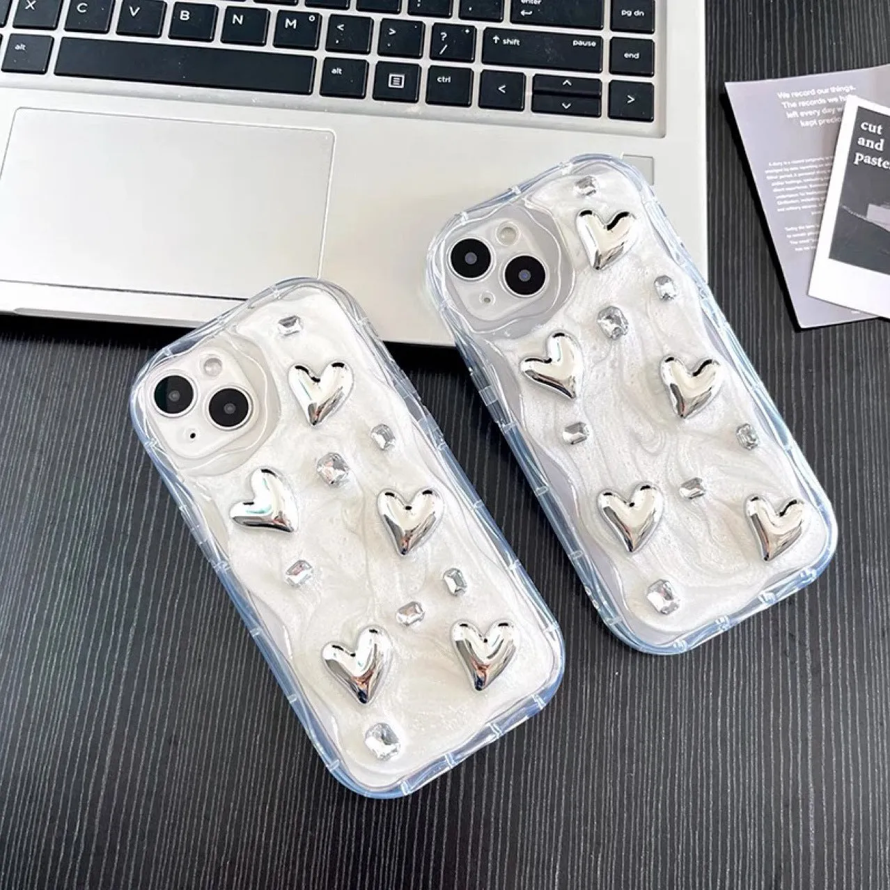 Transparent TPU phone case with three-dimensional silver love gem rhinestone heart design on white background
