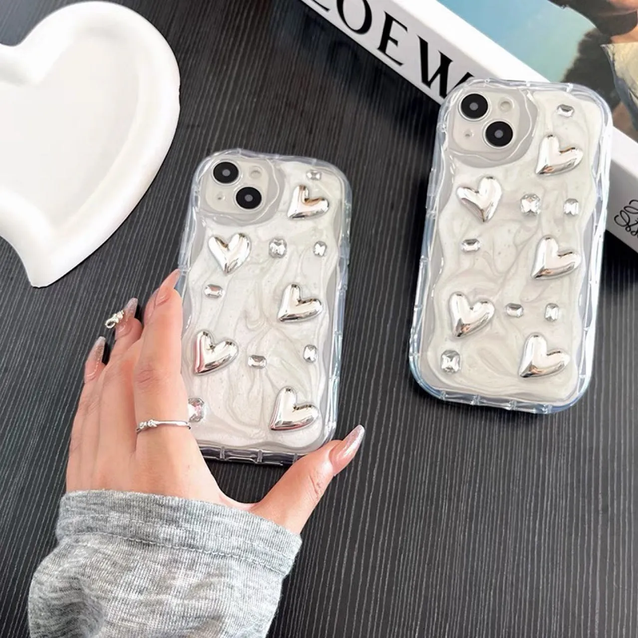 Transparent TPU phone case with three-dimensional silver love gem rhinestone heart design on white background