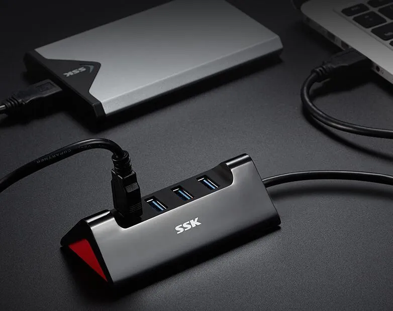 Black plastic USB hub with four USB-A ports and a Micro USB power port on a desk.