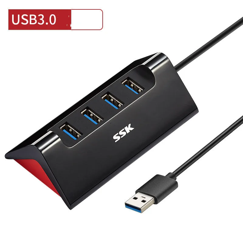 Black plastic USB hub with four USB-A ports and a Micro USB power port on a desk.