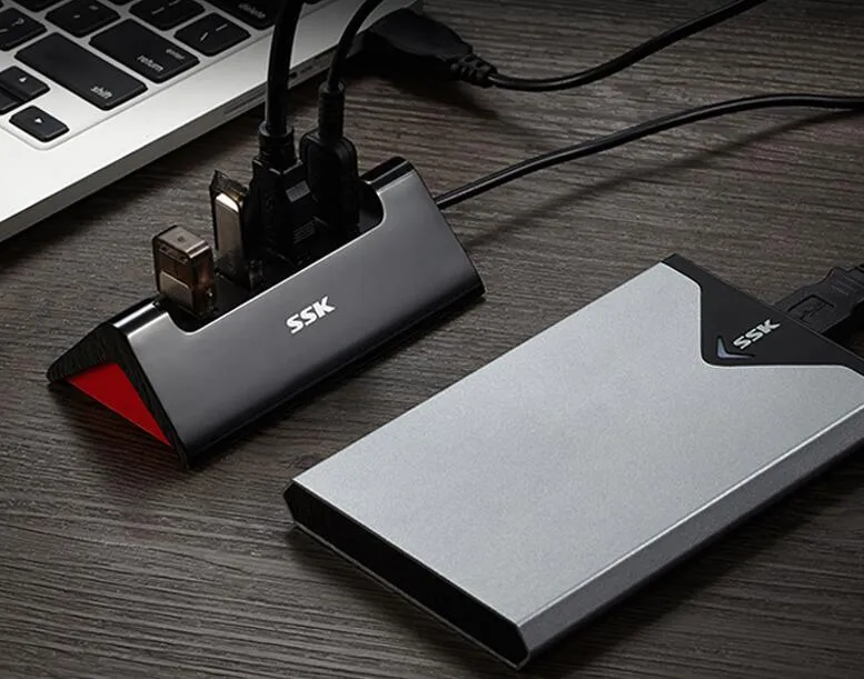 Black plastic USB hub with four USB-A ports and a Micro USB power port on a desk.