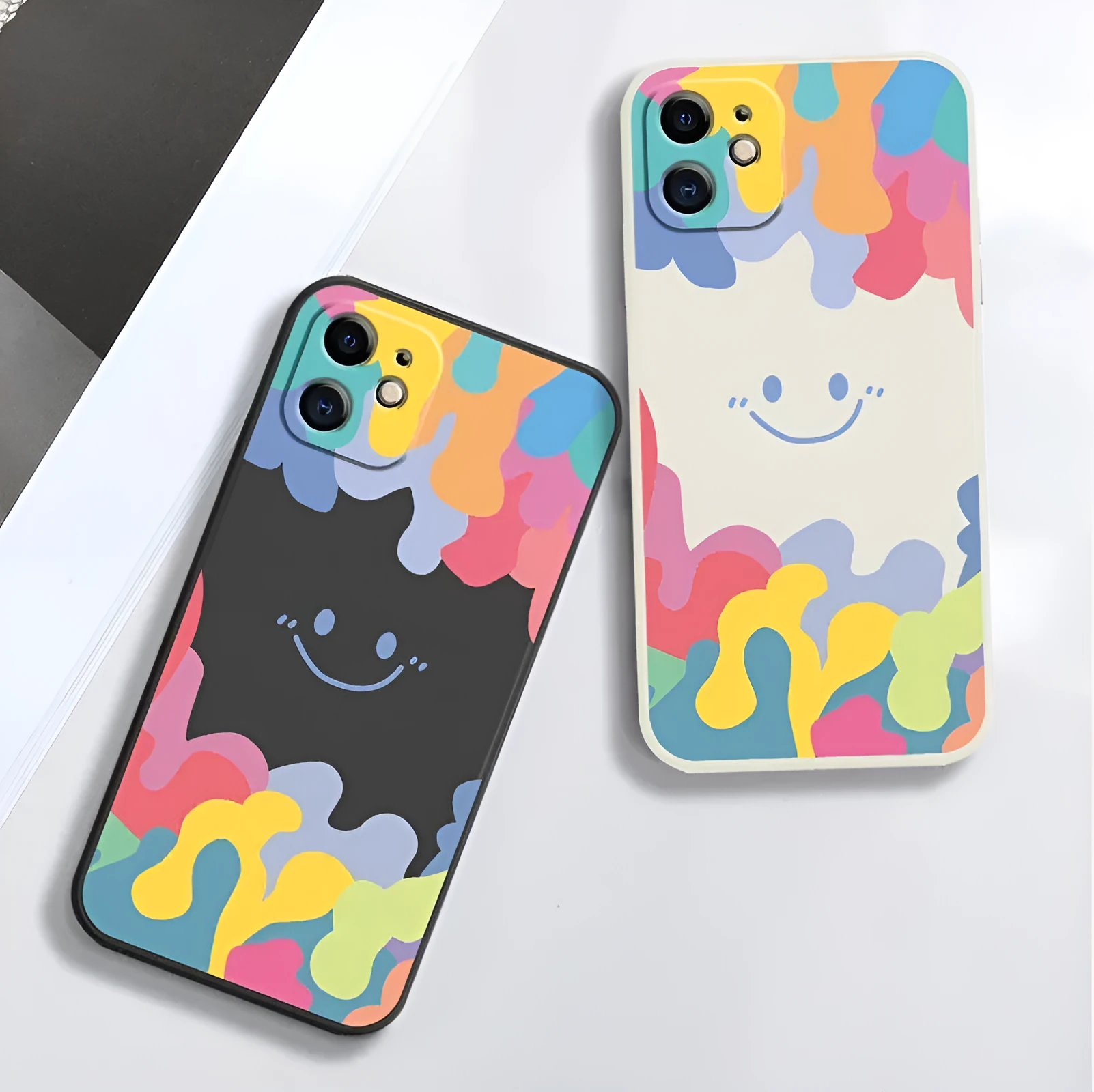 White silicone phone case with a rainbow smiley face design and a black lanyard attached.