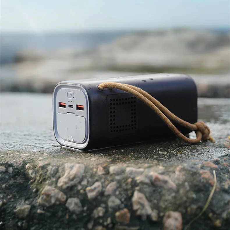 Black portable power bank with solar panel, showing size scale and output ports.