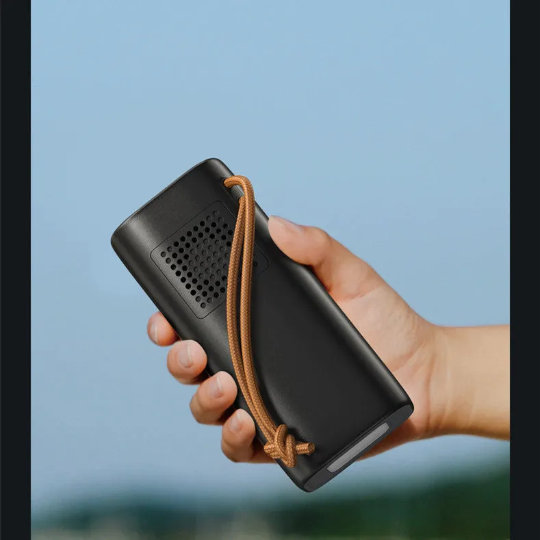 Black portable power bank with solar panel, showing size scale and output ports.