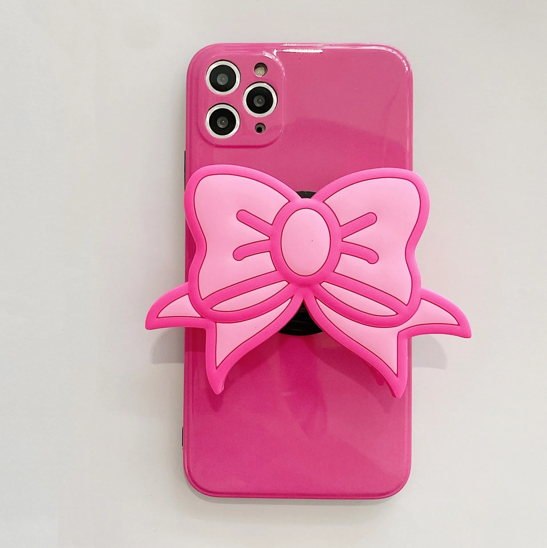 Rose red iPhone case with a large pink bow and a folded-out kickstand on the back.