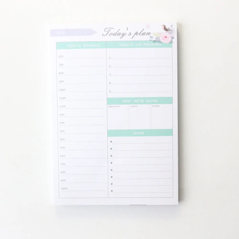 Domikee paper desk organiser pad open showing weekly and monthly planning templates with pink and green cover.