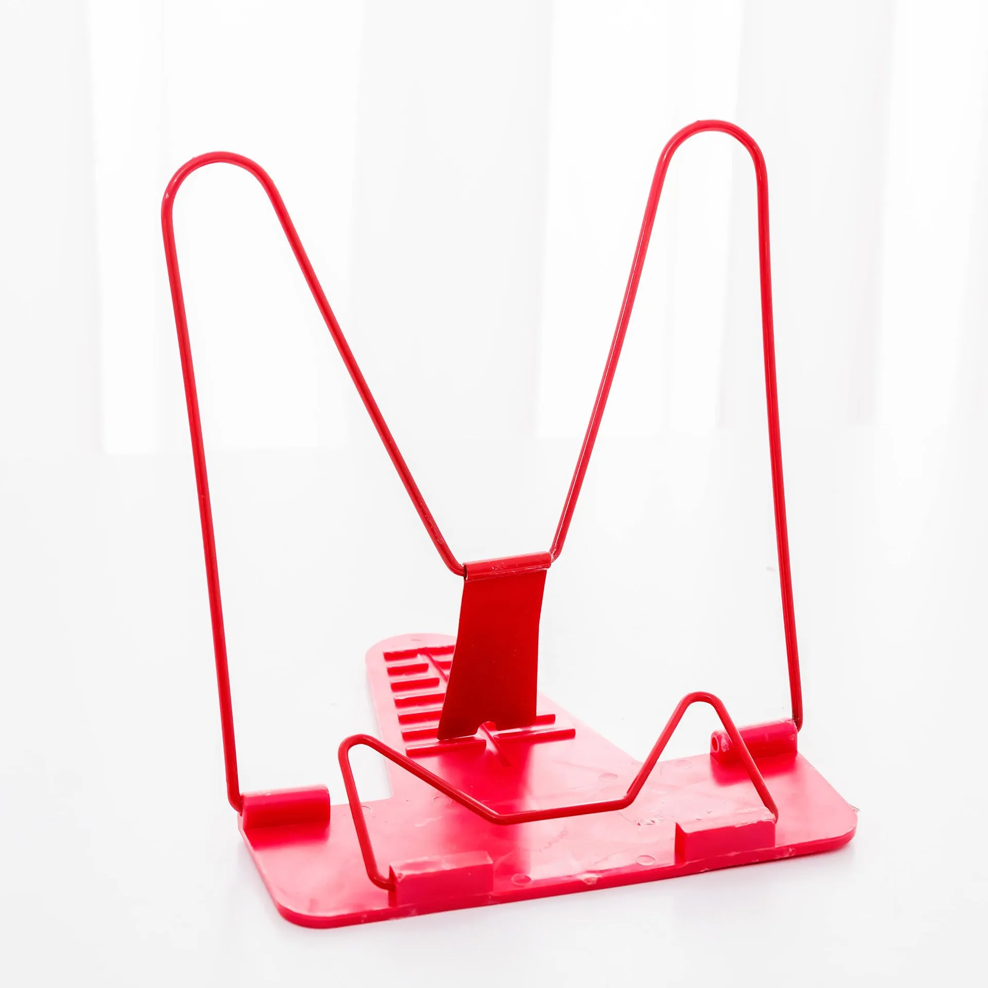 Red reading frame holding a book upright at an angle on a desk