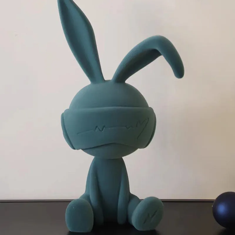Green suede blindfold rabbit resin ornament seated on a table
