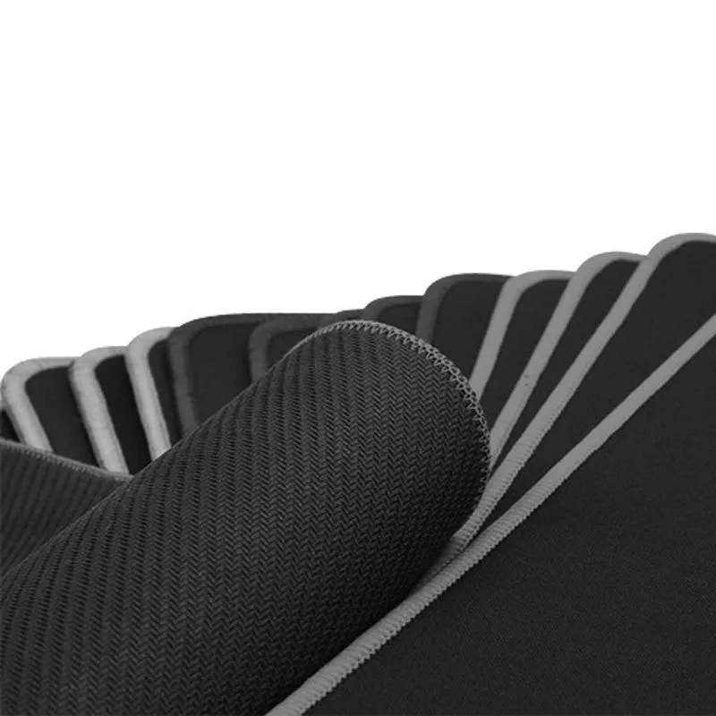All black extra long desk pad with overlock stitching on a wooden desk with keyboard and mouse