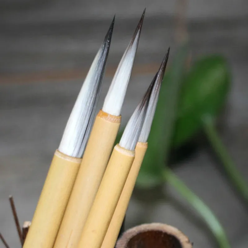 Set of four Chinese calligraphy brushes with gold pine branch design and mixed wolf hair and wool bristles