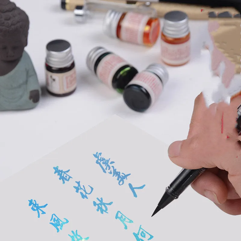 Set of six small glass bottles of gold powder dipping pen ink in different colours.