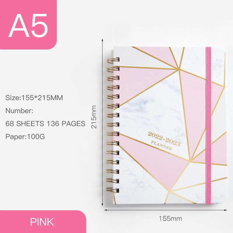 A5 spiral notebook with colourful floral cover, open to show lined pages and metal coil binding