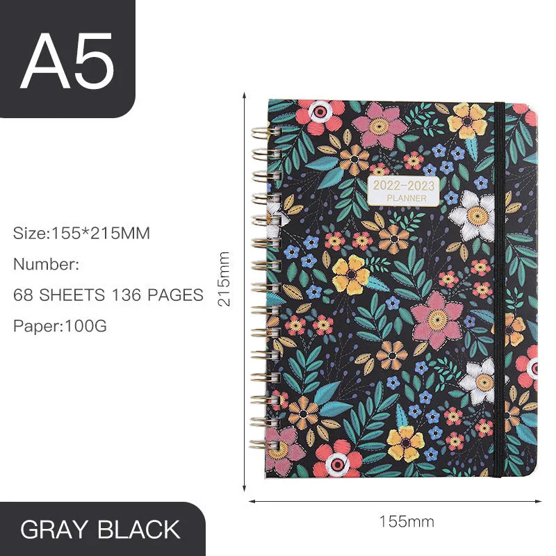 A5 spiral notebook with colourful floral cover, open to show lined pages and metal coil binding