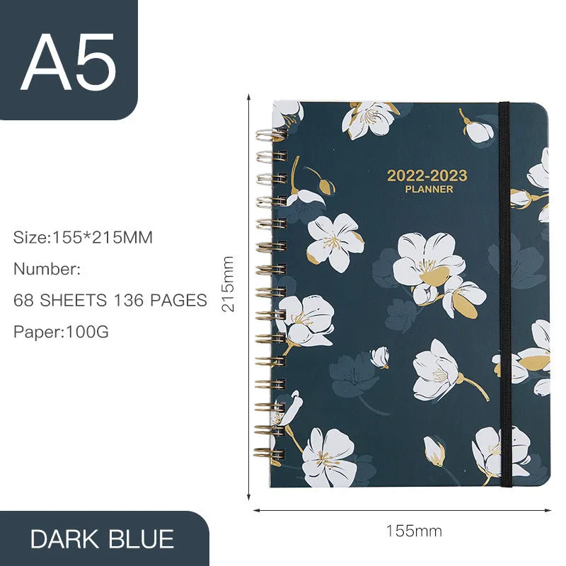 A5 spiral notebook with colourful floral cover, open to show lined pages and metal coil binding