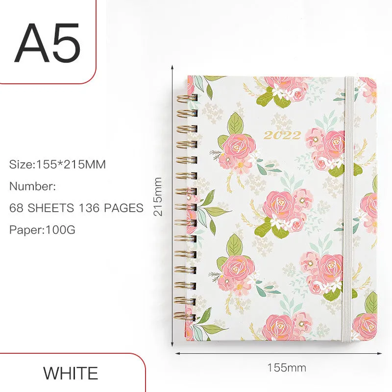A5 spiral notebook with colourful floral cover, open to show lined pages and metal coil binding