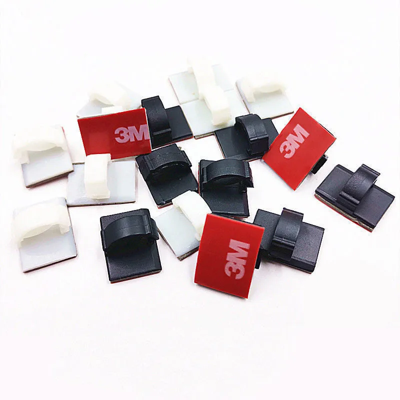 Black and white self-adhesive plastic flat cable clamps for wire organisation.