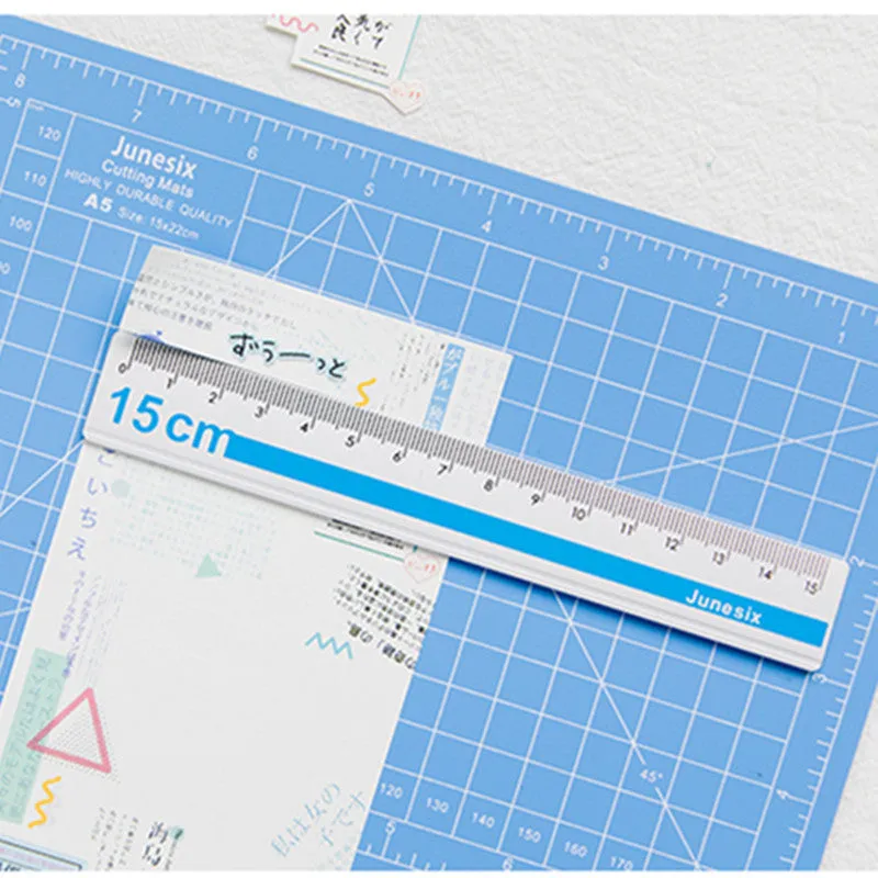 Art pen knife cutting board set in blue, showing plastic backing board with ruler, metal blade, and sharpener.