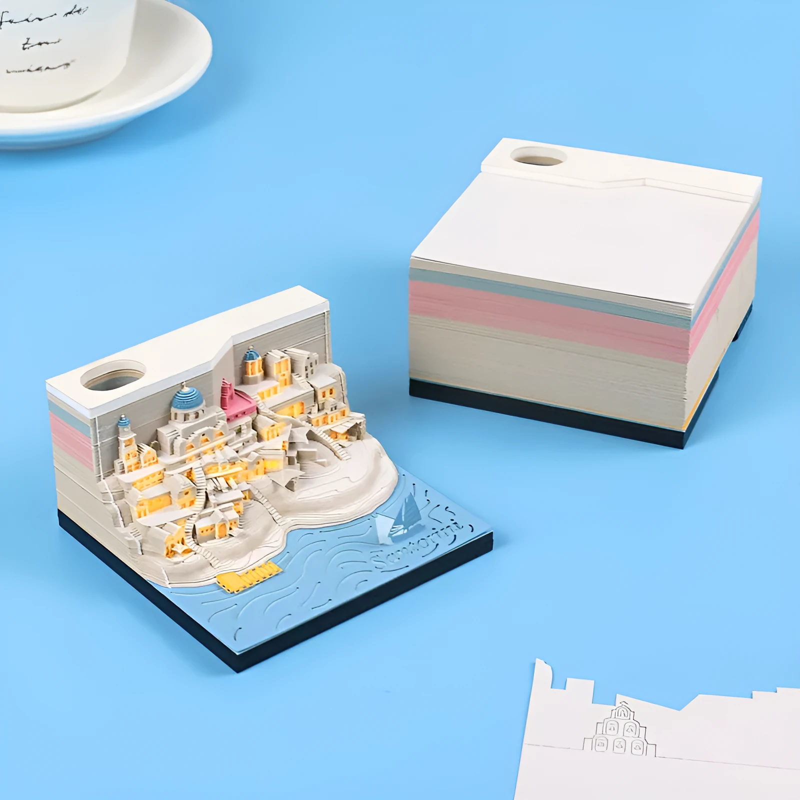 Assembled Santorini beach 3D paper model notepad with decorative lighting on a desk.