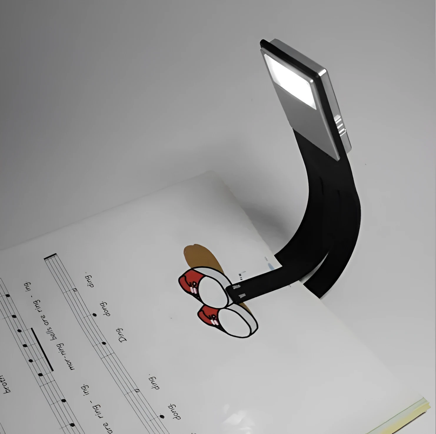Black plastic folding LED reading lamp shown open and closed, highlighting its thin 9mm profile.