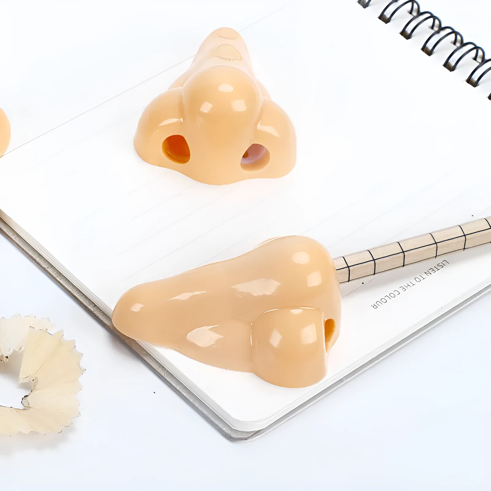 Flesh colour plastic manual pencil sharpener with big nostril hole on geometric body.