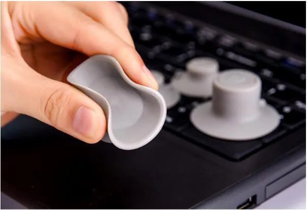 Set of four grey plastic non-slip cooling pads for laptops, two large and two small.