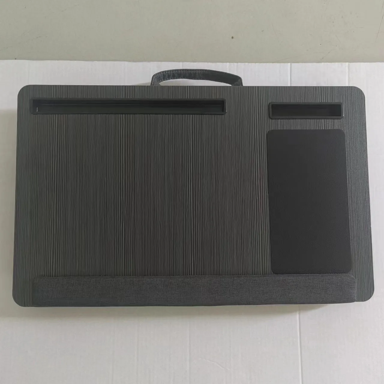 Foldable laptop desk in black walnut colour on a bed with laptop open