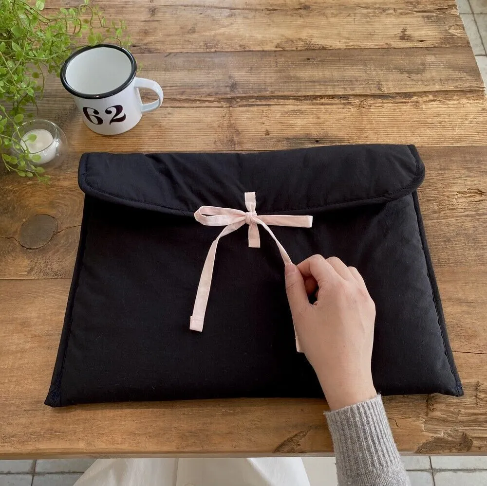 Black and white quilted women's laptop bag with a large decorative ballet bow on the front.