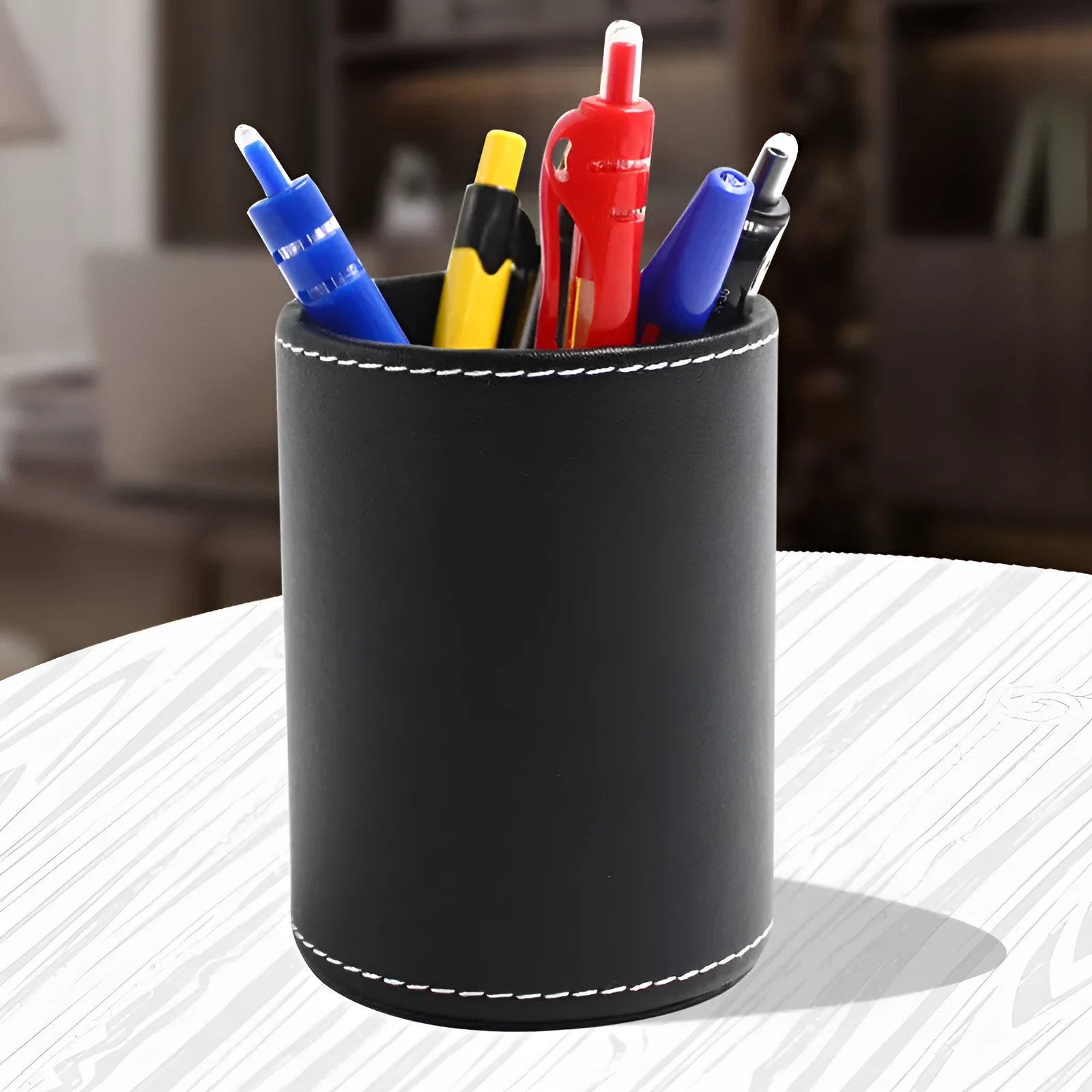 Black leather cylindrical pen holder measuring 8cm wide × 10.8cm tall on desk