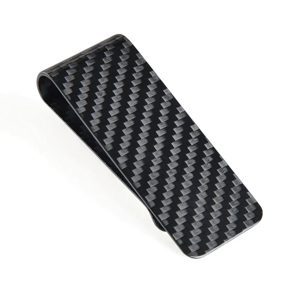 Glossy black genuine carbon fiber money clip on a flat surface, showing striped pattern and slim profile